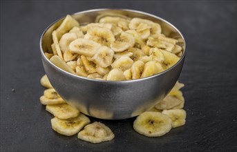 Portion of Dried Banana Chips on a rustic slate slab, selective focus, close-up shot