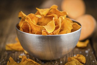 Sweet Potato Chips as high detailed close-up shot on a vintage wooden table, selective focus