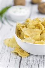 Potato Chips (Sour Cream taste) on a vintage background as detailed close-up shot (selective focus)