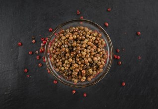 Some Pink Peppercorns (preserved) on a slate slab as detailed close-up shot, selective focus