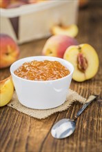 Homemade Peach Jam on an wooden table as detailed close-up shot, selective focus