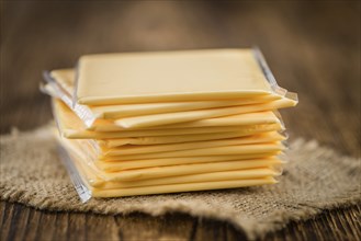 Cheese (sliced) on an old wooden table as detailed close-up shot (selective focus)