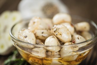 Marinated Garlic on an old wooden table as detailed close-up shot (selective focus)