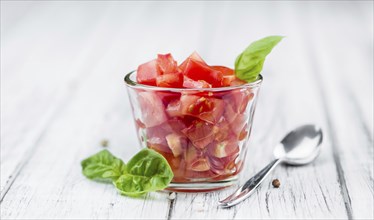 Tomatoes (diced) as high detailed close-up shot on a vintage wooden table (selective focus)