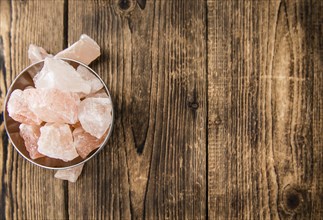 Wooden table with a portion of pink Salt (close-up shot, selective focus)