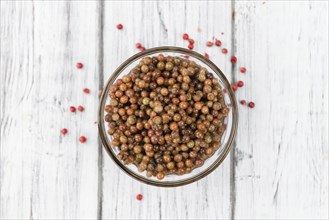 Fresh made Pink Peppercorns (preserved) on an old and rustic wooden table, selective focus,