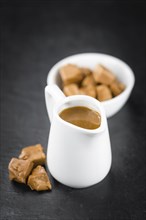 Portion of Caramel Sauce as detailed close up shot on a slate slab (selective focus)