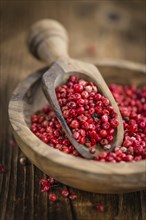 Pink Peppercorns as high detailed close-up shot on a vintage wooden table, selective focus