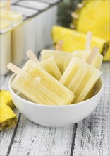 Old and rustic wooden table with homemade Pineapple Pipsicles (selective focus, close-up shot)