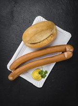 Portion of Sausages (Frankfurter) as detailed close up shot on a slate slab (selective focus)