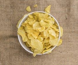 Potato Chips (Sour Cream taste) on a vintage background as detailed close-up shot (selective focus)