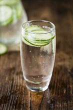 Fresh made Cucumber Water as high detailed close-up shot on a vintage wooden table, selective focus