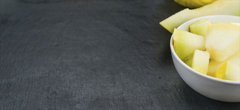 Portion of Honeydew Melon as detailed close up shot on a slate slab (selective focus)