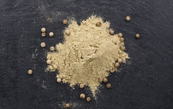 Portion of White Pepper as detailed close up shot on a slate slab, selective focus