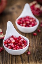 Pomegranate on an old wooden table as detailed close-up shot (selective focus)