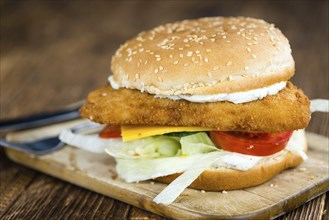 Fish Burger (selective focus, close-up shot) on wooden background