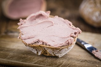 Roll with Liverwurst (German cuisine) on an old wooden table as detailed close-up shot (selective