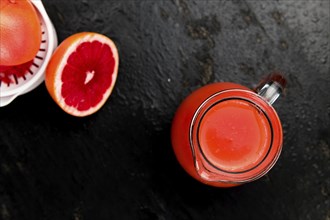 Some freshly squeezed Grapefruit Juice on a vintage background (close-up shot, selective focus)