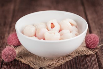 Lychees (preserved) as high detailed close-up shot on a vintage wooden table (selective focus)