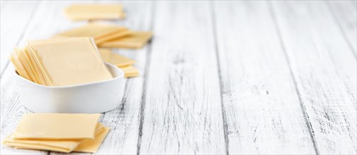 Cheese (sliced) on an old wooden table as detailed close-up shot (selective focus)