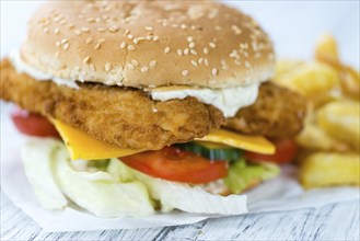 Wooden table with a fresh made Fish Burger (close-up shot, selective focus)