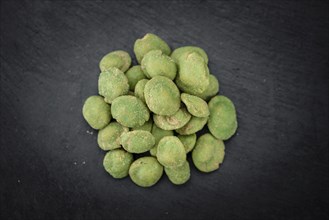 Portion of Wasabi coated Peanuts on a rustic slate slab (selective focus, close-up shot)