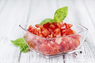 Tomatoes (diced) as high detailed close-up shot on a vintage wooden table (selective focus)