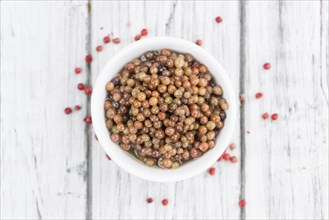 Preserved Pink Peppercorns on a vintage background as detailed close-up shot, selective focus