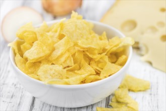 Cheese and Onion Potato Chips on an old wooden table as detailed close-up shot (selective focus)