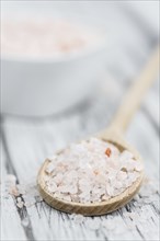 Salt (pink) on an old wooden table as detailed close-up shot (selective focus)