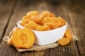 Dried Food (Apricots) on rustic wooden background (close-up shot)