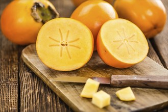 Kaki fruits on rustic wooden background (close-up shot)