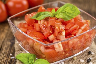 Tomatoes (diced) as high detailed close-up shot on a vintage wooden table (selective focus)