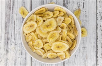 Homemade Dried Banana Chips on an wooden table as detailed close-up shot, selective focus