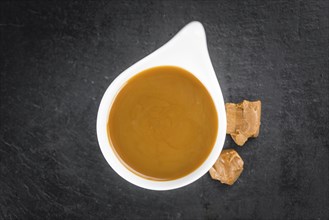 Caramel Sauce on a vintage background as detailed close-up shot (selective focus)