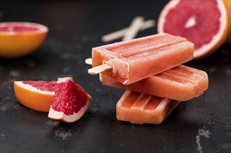 Vintage slate slab with some freshly made Grapefruit Popsicles (selective focus, close-up shot)