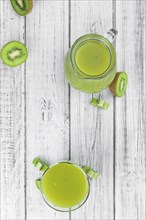 Wooden table with fresh made Kiwi Smoothie (close-up shot, selective focus)