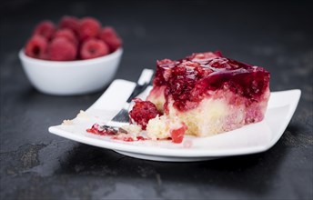 Fresh made portion of Raspberry Cake (selective focus, close-up shot) on rustic background