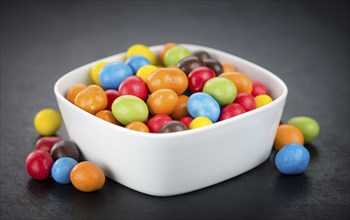 Portion of Cocolate coated Peanuts as detailed close up shot on a slate slab (selective focus)