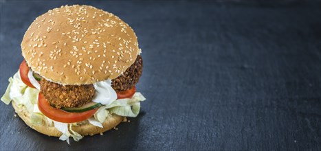 Homemade Falafel Burger on a dark slate slab (close-up shot, selective focus)