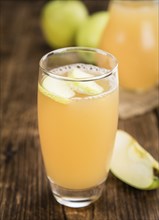 Homemade Apple Juice on an wooden table (selective focus) as detailed close-up shot