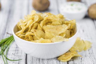 Potato Chips with Sour Cream taste as high detailed close-up shot on a vintage wooden table