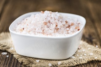 Salt (pink) on an old wooden table as detailed close-up shot (selective focus)