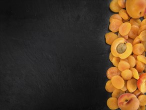 Portion of Dried Food (Apricots) as detailed close up shot on a slate slab (selective focus)