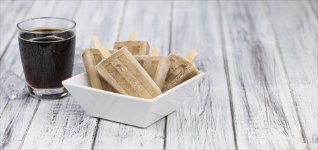 Fresh made Cola Popsicles on wooden background (selective focus, close-up shot)