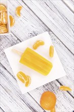 Portion of fresh homemade Tangerine Popsicles (close-up shot, selective focus) on a vintage