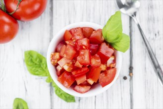 Tomatoes (diced) as high detailed close-up shot on a vintage wooden table (selective focus)