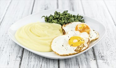 Some homemade Mash (selective focus) as detailed close-up shotwith fried eggs and spinach