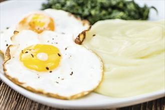 Some homemade Mash with fried eggs and spinach (selective focus) as detailed close-up shot)