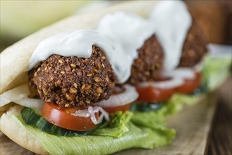 Fresh made Falafel Sandwich (close-up shot, selective focus) on an old wooden table